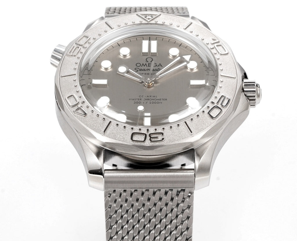 Stainless steel diver watch with textured bezel and gray mesh bracelet, front view.