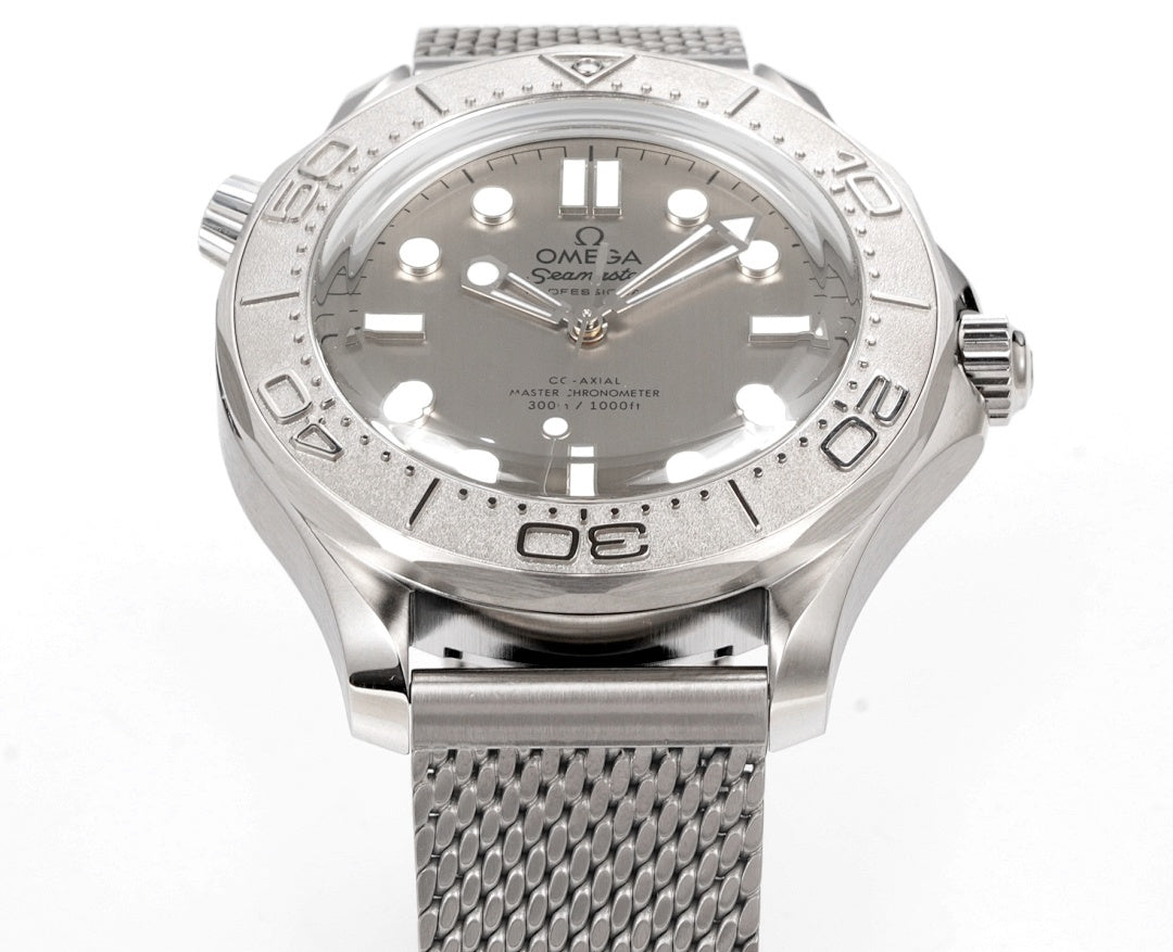 Stainless steel diver watch with textured bezel and gray mesh bracelet, front view.