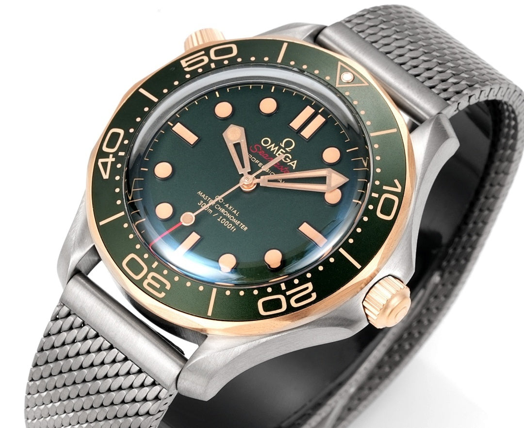 Omega watch close-up with green dial, gold bezel numerals, metal mesh bracelet