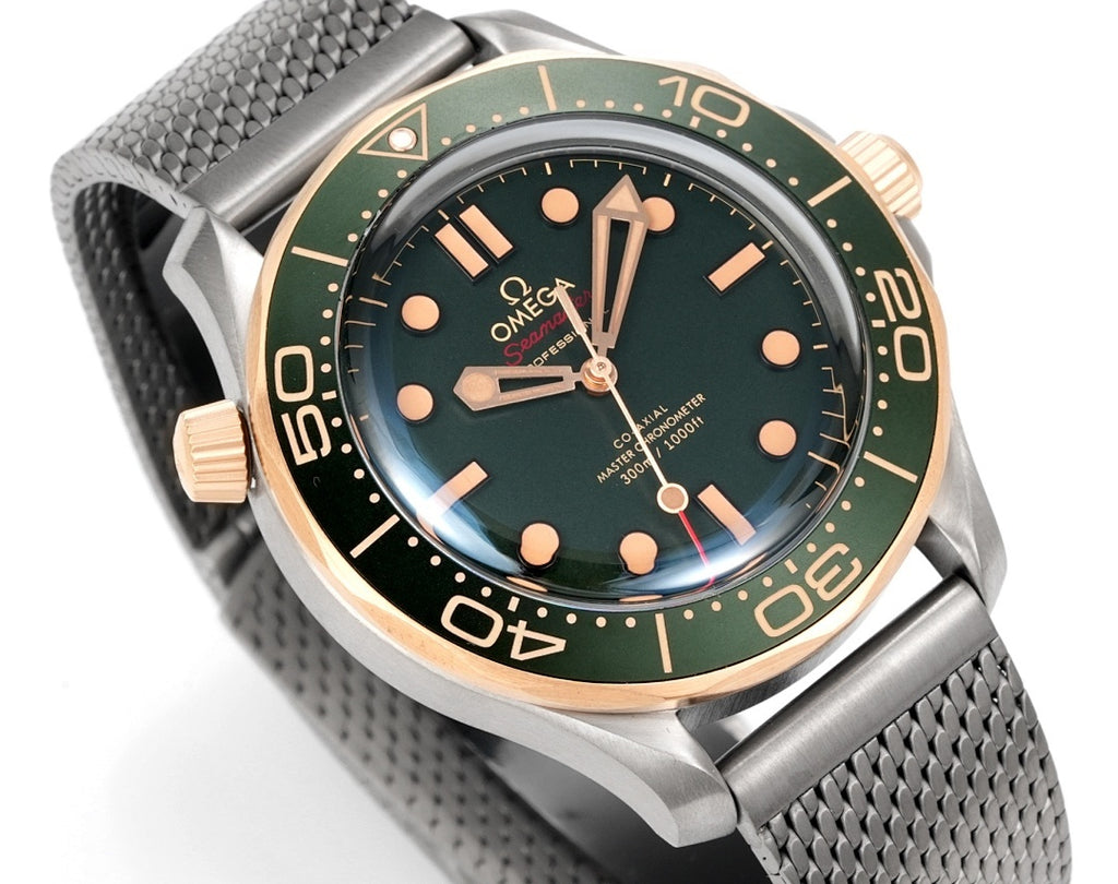 Omega watch angled view with green dial, gold-tone indices and hands, metal mesh strap