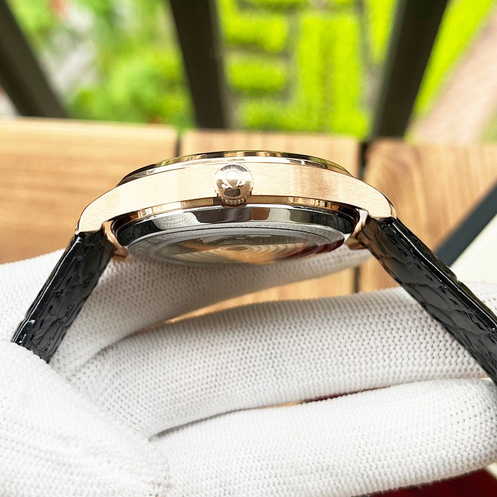 Omega De Ville wristwatch top view with rose-gold case and black leather strap.