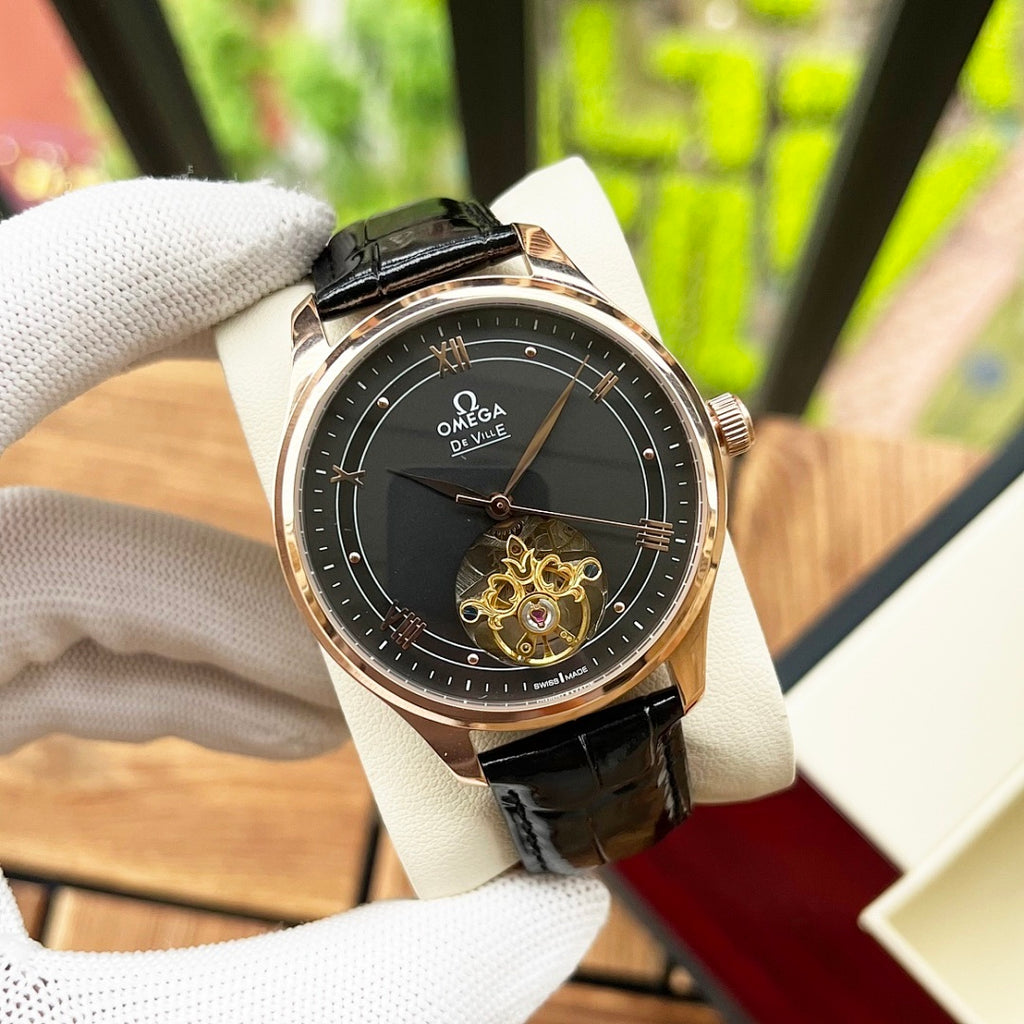 Omega De Ville wristwatch with black dial, rose-gold case, black leather strap.