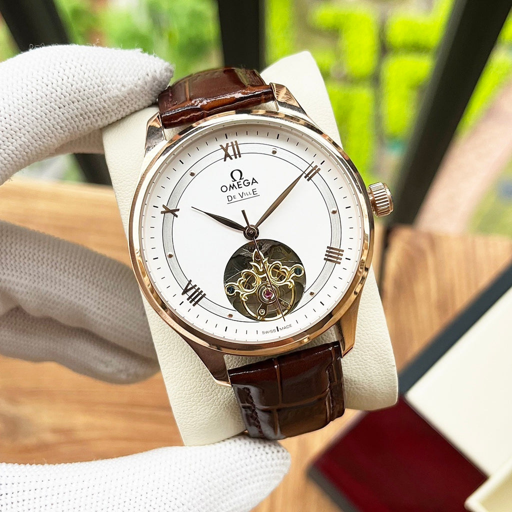 Omega De Ville wristwatch with white dial, rose-gold case, brown leather strap.
