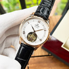 Omega De Ville wristwatch close-up with white dial, black leather strap, rose-gold case.