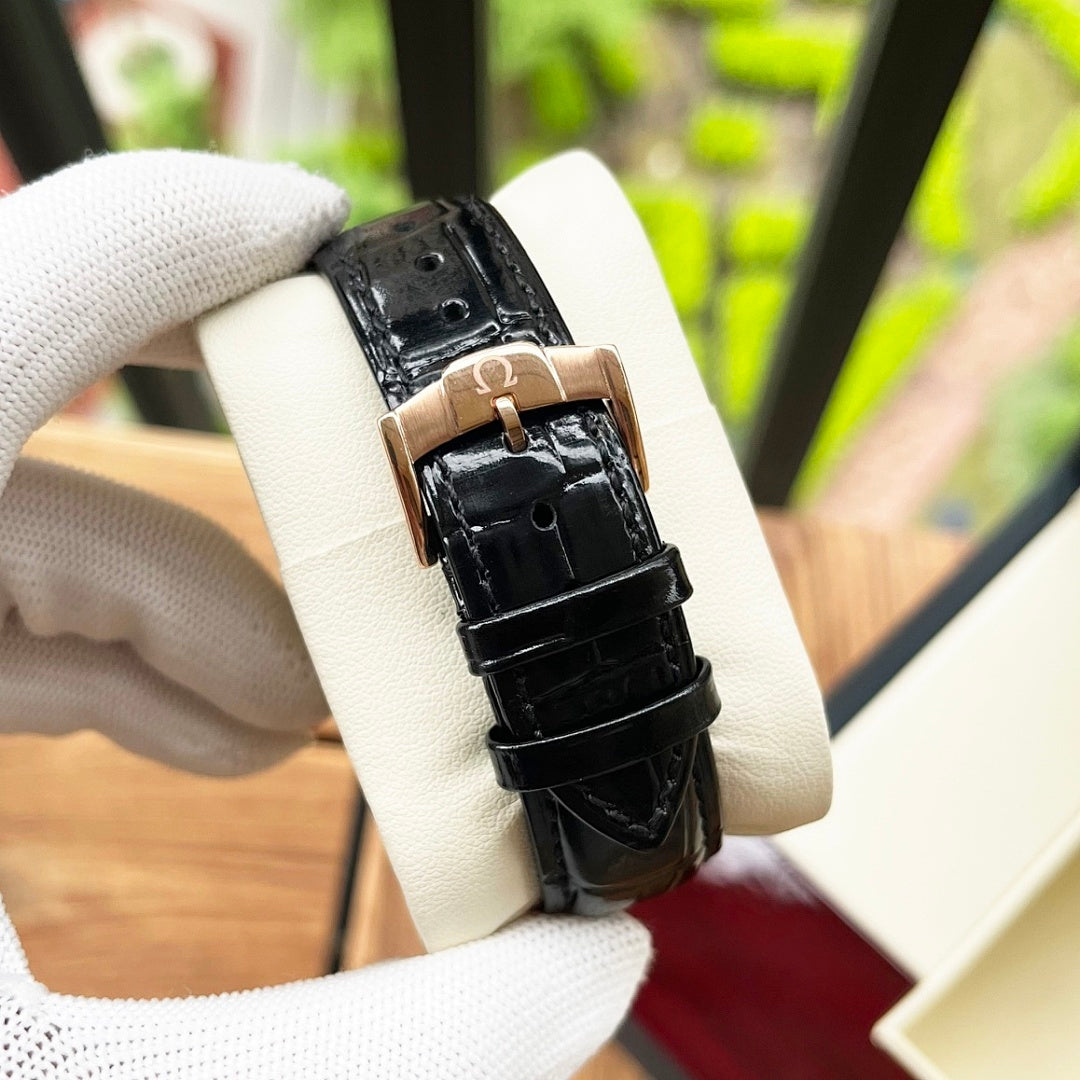 Omega De Ville wristwatch close-up with black crocodile-style leather strap and rose-gold buckle.