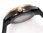 Rose-gold bezel diver watch with black strap; underside view of case and crown.