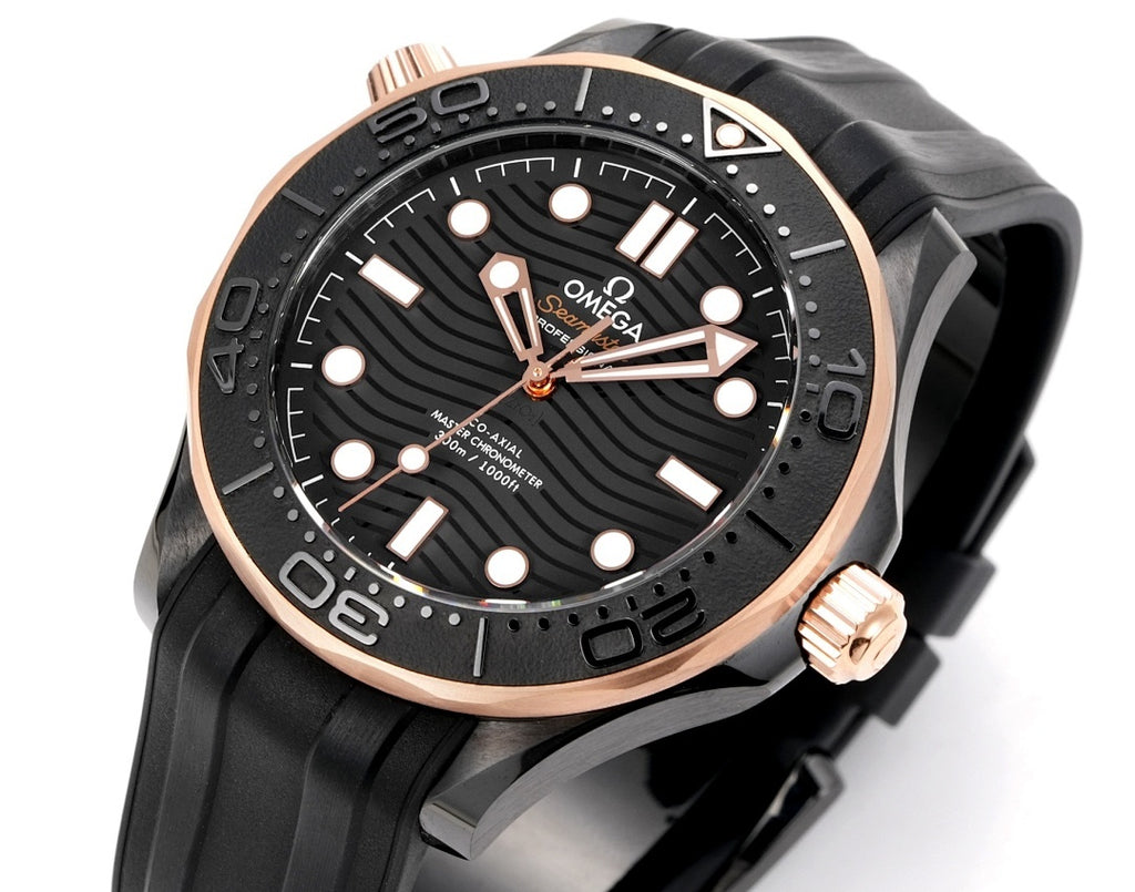 Black rubber diver watch front with rose-gold bezel, dark dial, and five gold-tone markers.