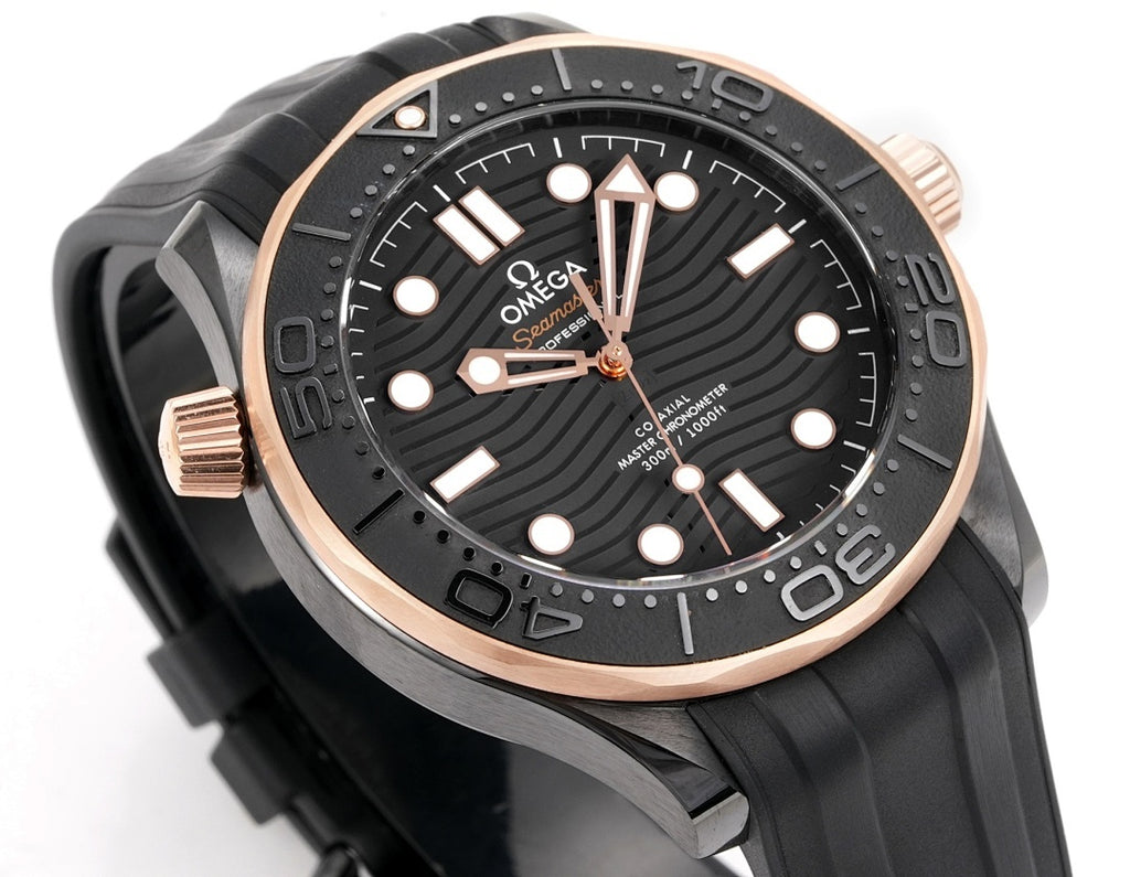 Black diver watch with rose-gold bezel and crown guards; dial with luminous dot markers.