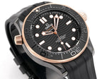 Black diver watch with rose-gold bezel and crown guards; dial with luminous dot markers.