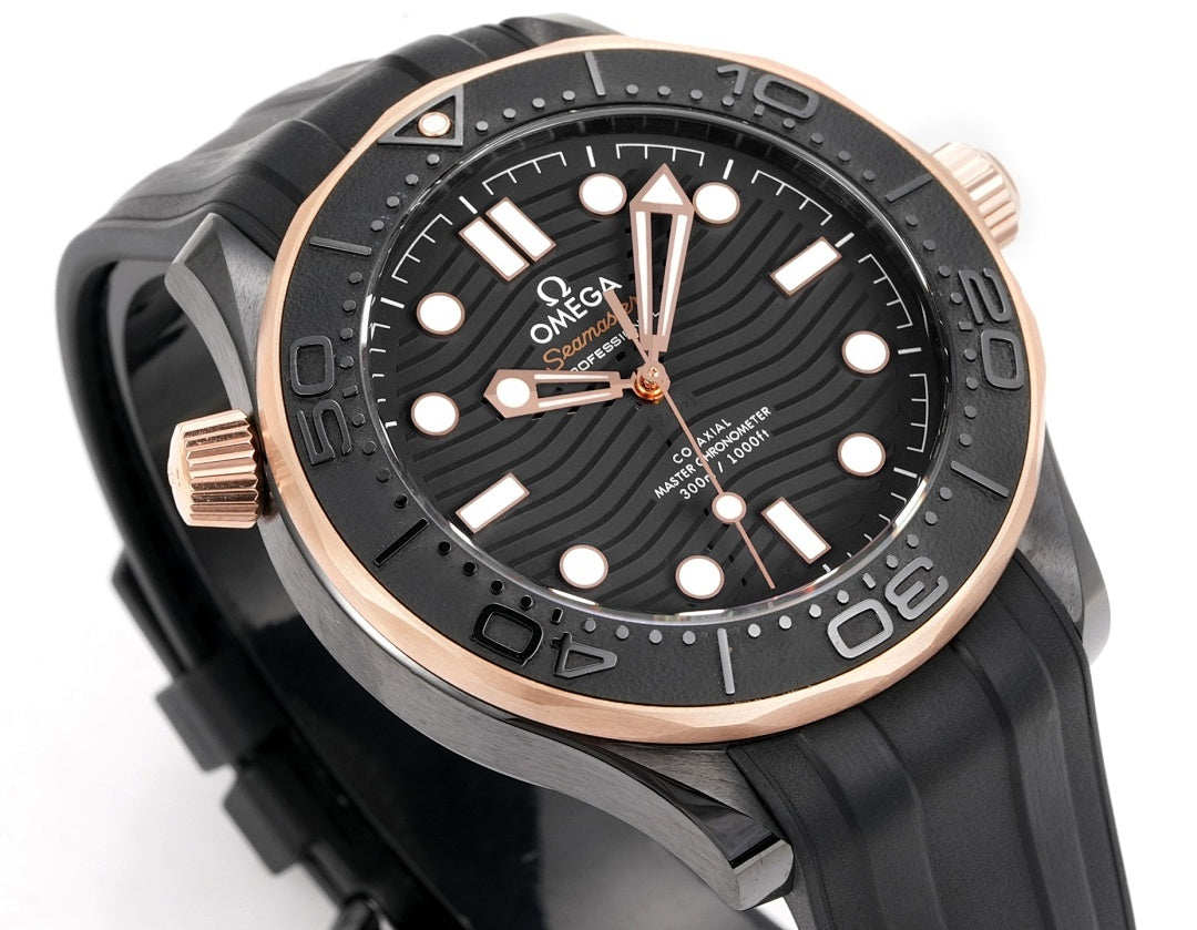 Black diver watch with rose-gold bezel and crown guards; dial with luminous dot markers.
