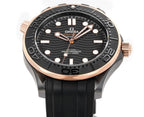 Front view of black rubber diver watch with rose-gold bezel and circular black dial.