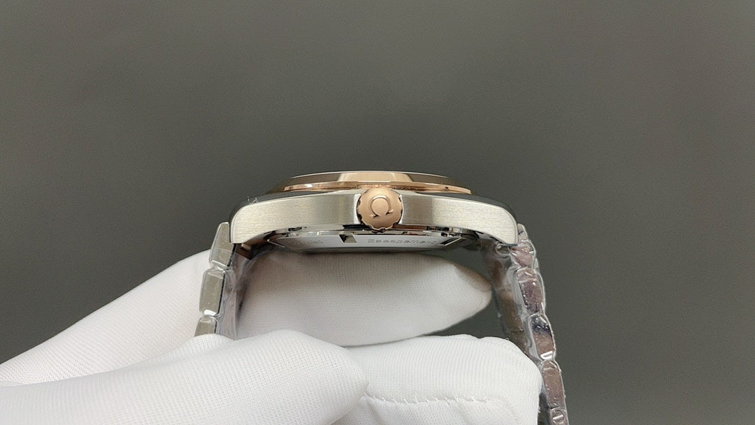 Steel wristwatch caseback detail with gold-toned crown, held by white glove