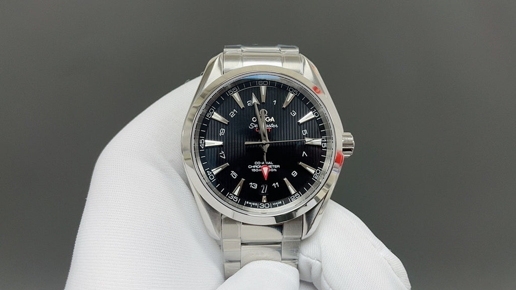 Steel wristwatch with dark dial and gold bezel, shown on white glove