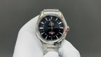 Steel wristwatch with dark dial and gold bezel, shown on white glove