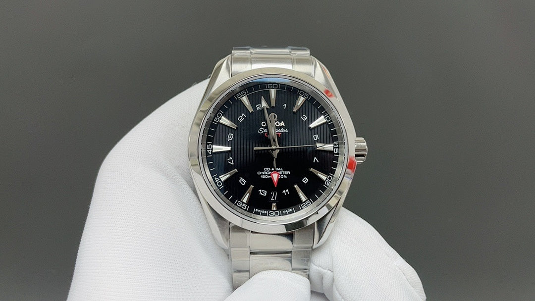 Steel wristwatch with dark dial and gold bezel, shown on white glove