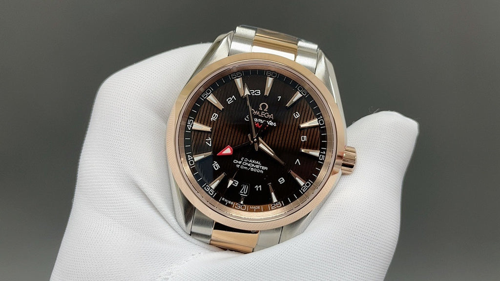 Two-tone rose-gold and steel wristwatch with dark dial, held on white glove
