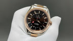 Two-tone rose-gold and steel wristwatch with dark dial, held on white glove