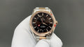Rose-gold and steel wristwatch with dark dial, gold bezel, and three hands