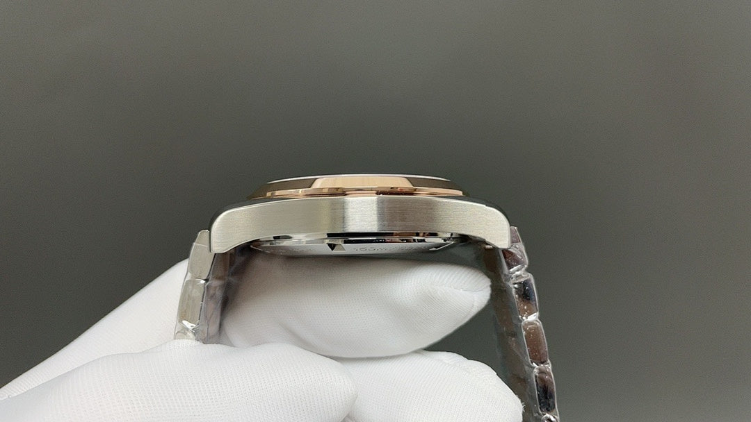 Steel wristwatch caseback with gold-toned bezel ring, held by white glove