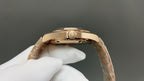Gold wristwatch case top and crown detail, metal link band visible