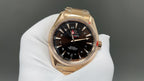 Gold Omega wristwatch with black dial, red seconds hand and date window