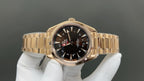 Gold wristwatch with black dial, baton hour markers and red seconds hand