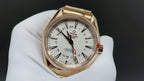 Gold wristwatch with white dial, black hands and red seconds hand