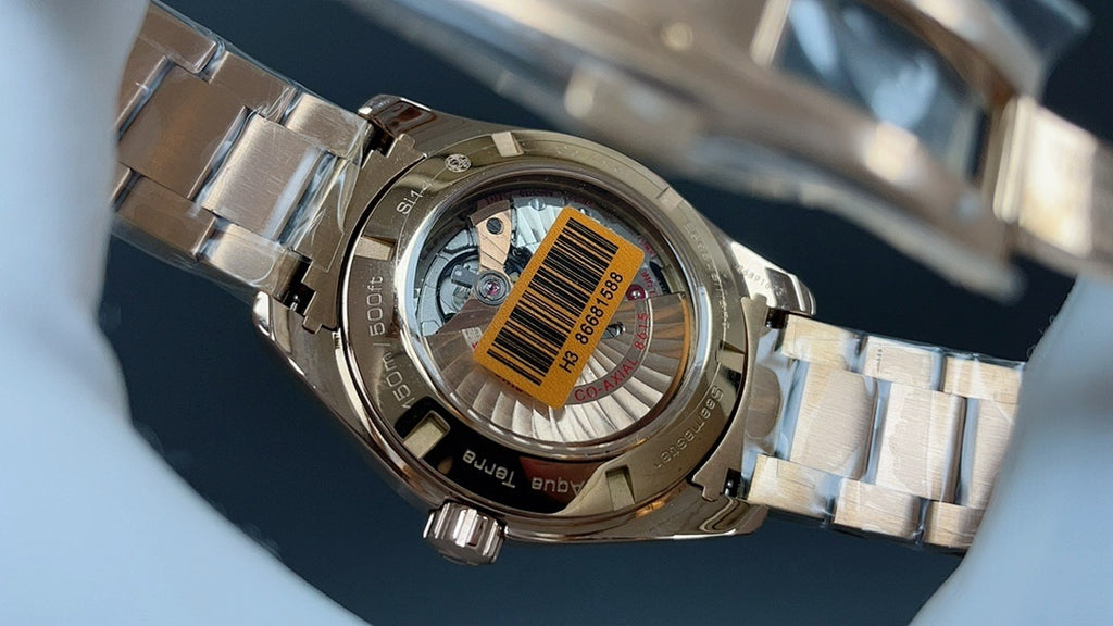 Gold wristwatch with steel bracelet, see-through caseback with barcode sticker visible
