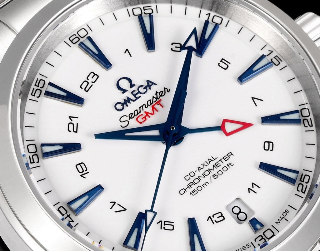 Close-up of white watch dial with blue hour hands and red seconds accent on metal bezel.