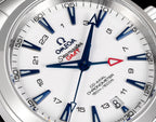 Close-up of white watch dial with blue hour hands and red seconds accent on metal bezel.