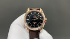 Analog wristwatch with black dial, gold-tone bezel, and brown leather strap