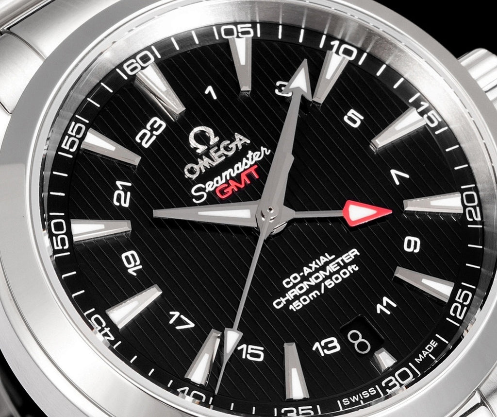 Black dial close-up with red arrow seconds hand and silver hour markers