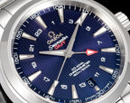 Close-up of blue watch dial with silver hands, logos, and minute markers on a sunray texture.