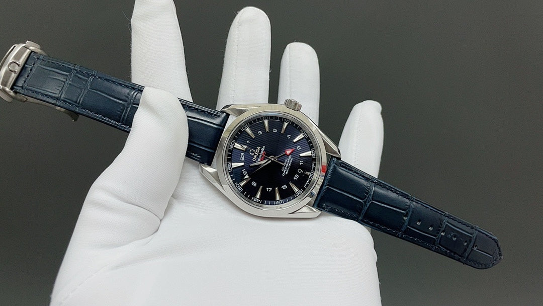 Wristwatch on blue leather strap held in gloves, silver case and dark dial