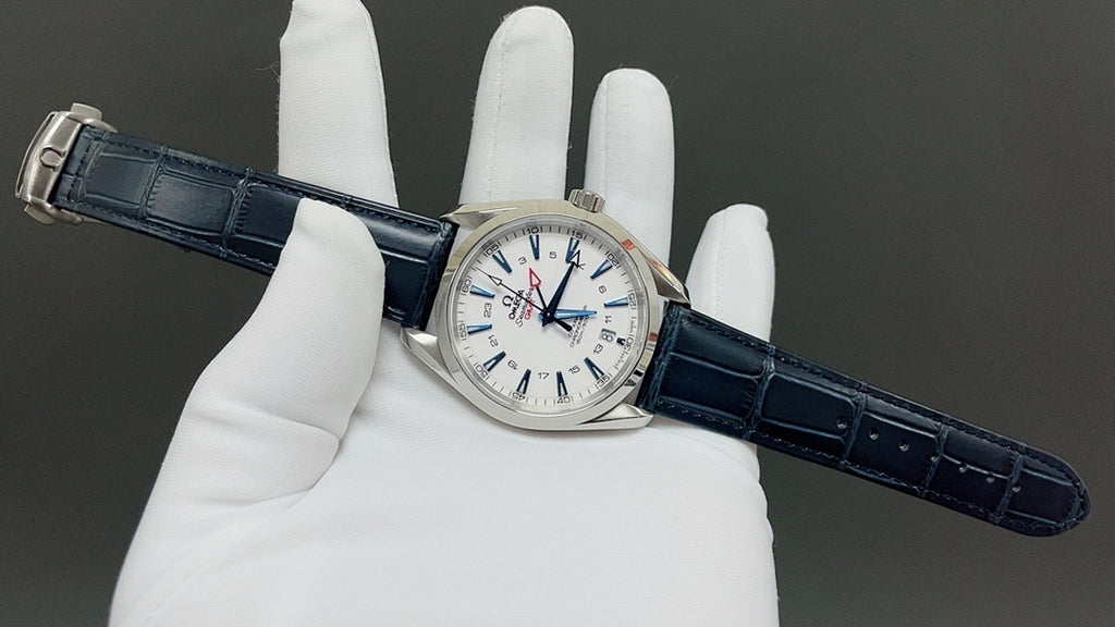 Wristwatch on blue leather strap held in gloves, white dial with red details