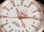 Omega wristwatch dial close-up with white face, hour markers, and red GMT hand.