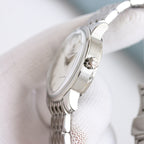 Stainless steel Omega watch case with crown and curved bezel, on white knit
