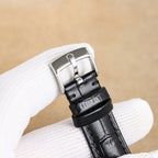 Silver analog wristwatch with black leather strap, side profile and clasp detail