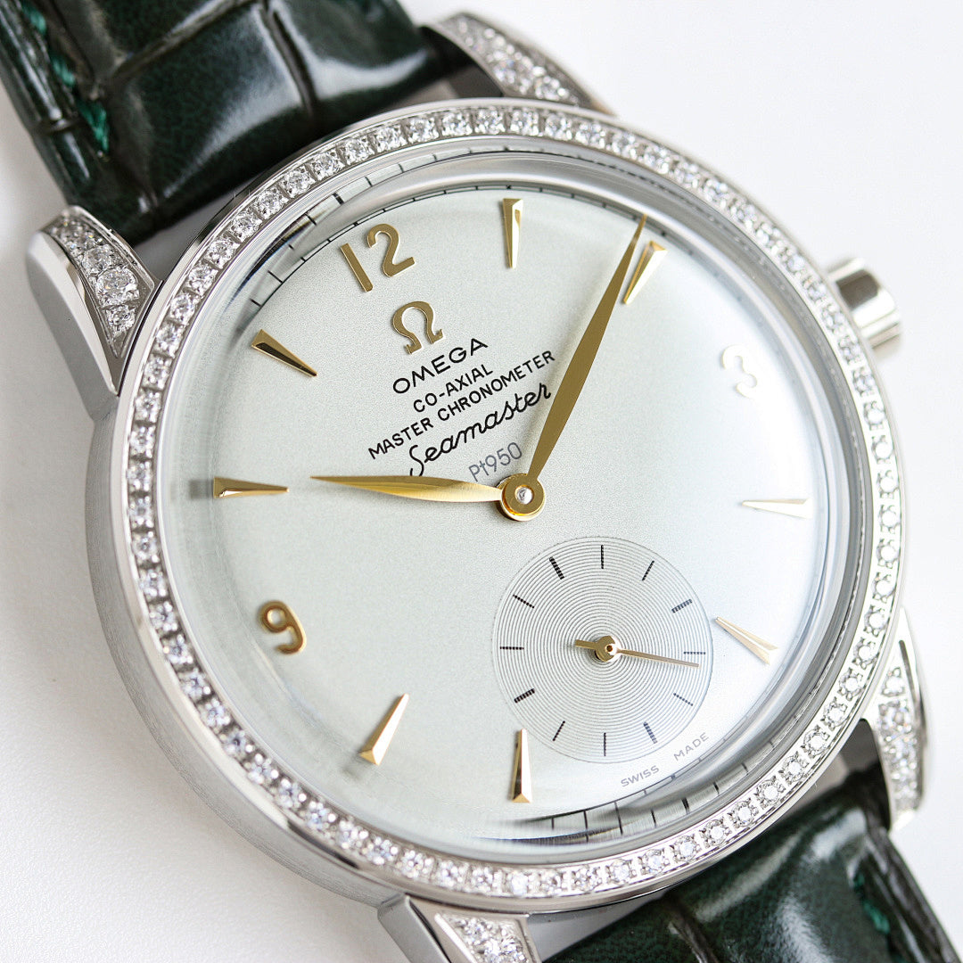 Silver watch close-up with green leather strap, diamond bezel, gold details on white dial.