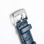 Silver watch case with blue leather strap, side view.