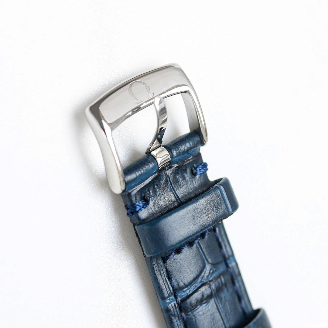 Silver watch case with blue leather strap, side view.