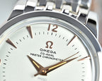 Close-up of silver wristwatch face with white dial, brown-gold hour markers and hands