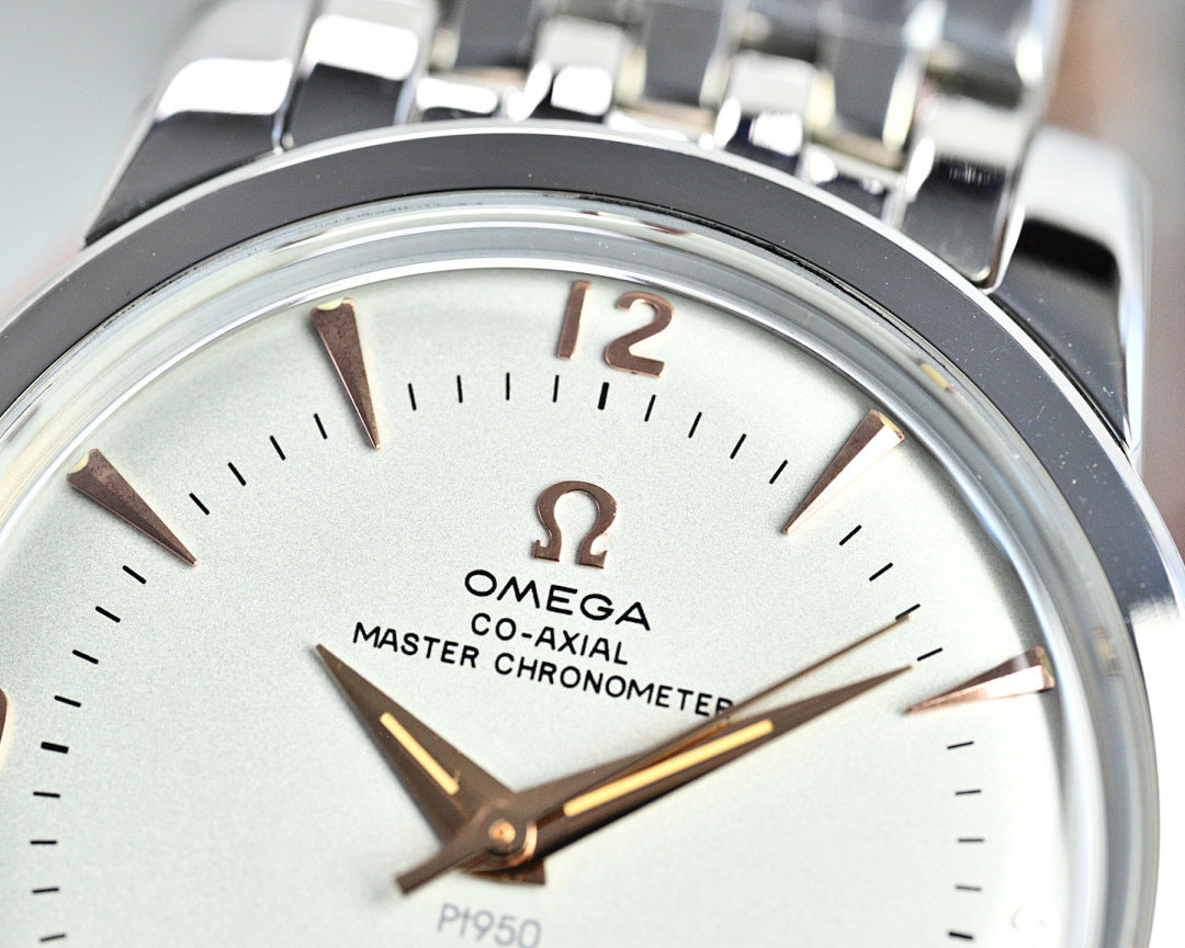 Close-up of silver wristwatch face with white dial, brown-gold hour markers and hands