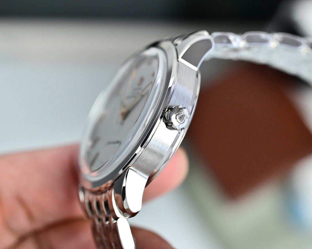 Silver wristwatch side view with crown and metal bracelet, held in a hand