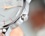 Close-up of silver wristwatch crown area and case edge, metal bracelet
