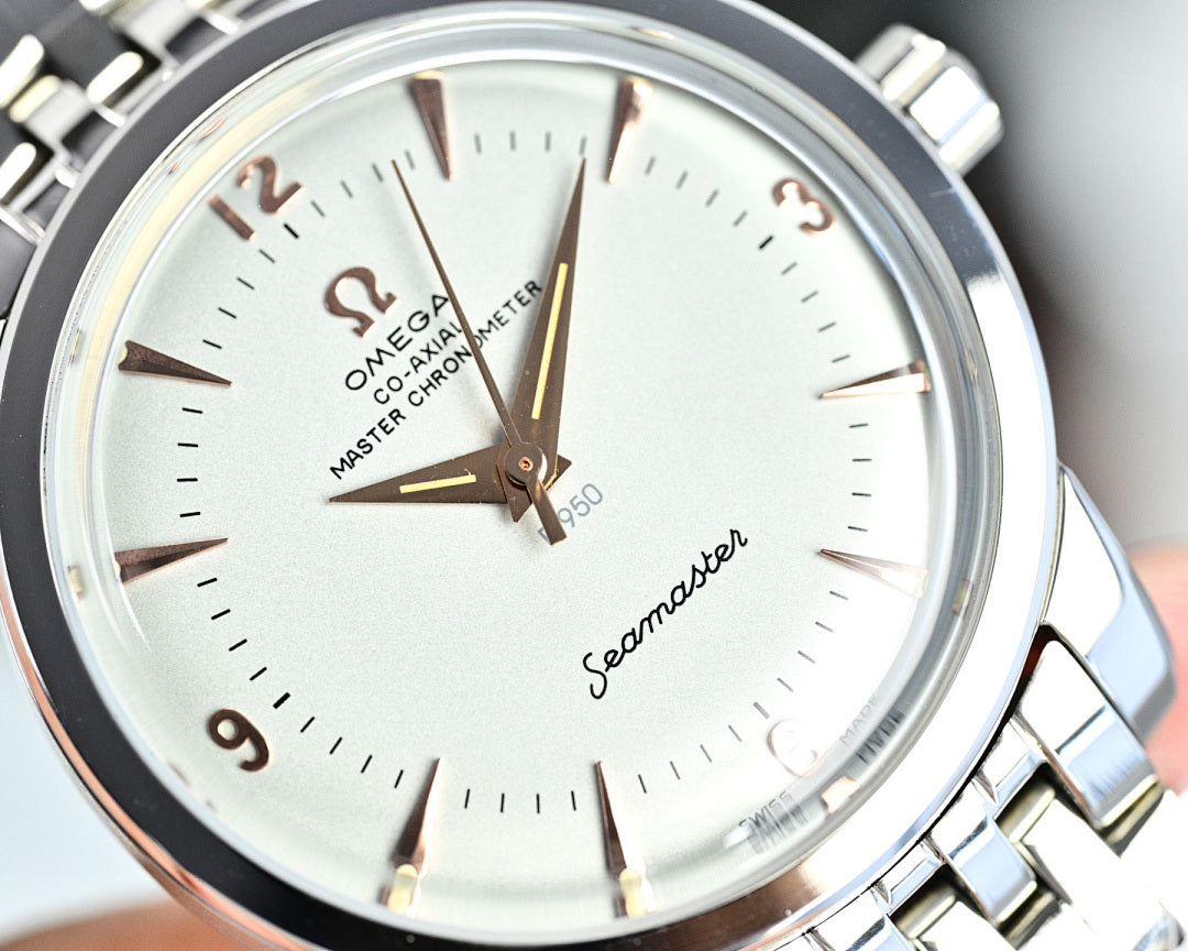 Silver wristwatch face close-up with white dial, gold markers, and gold hands
