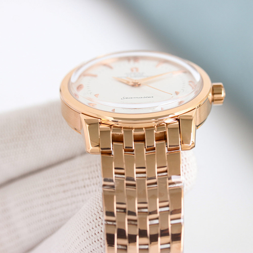 Omega Seamaster watch with gold bezel, white dial, and gold bracelet