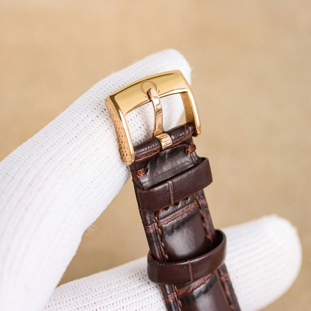 Brown leather watch strap with rose-gold buckle and case side detail