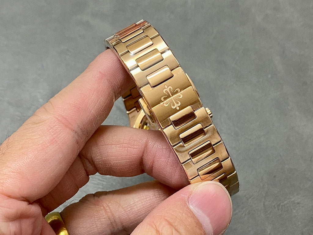 Patek Philippe gold-tone bracelet with engraved links, held in hand