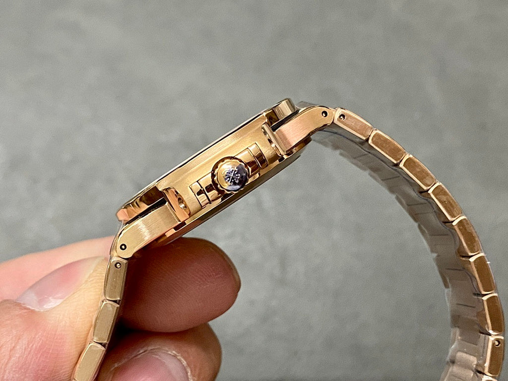 Patek Philippe watch clasp and caseback, gold-tone bracelet held upright